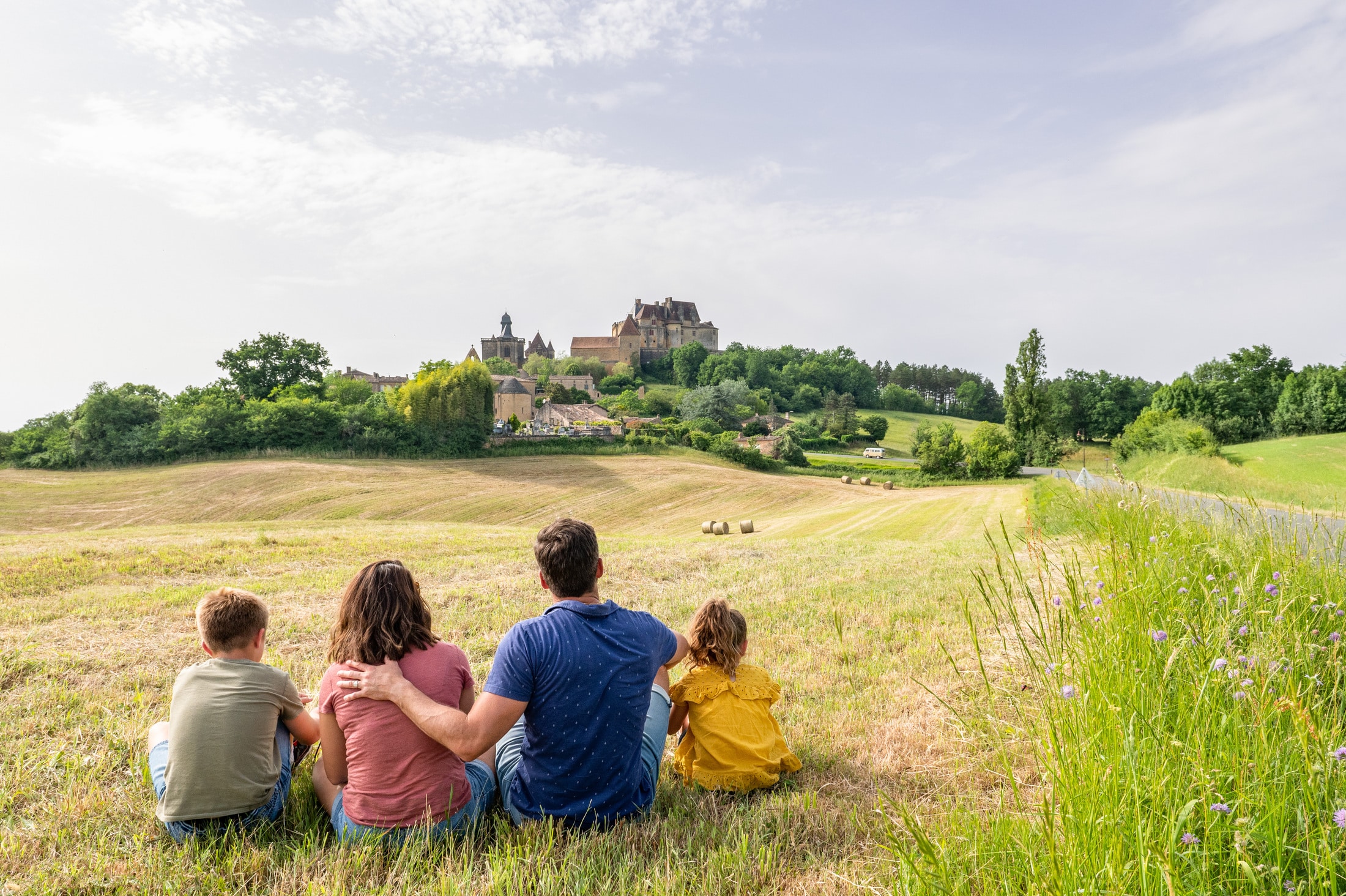 famille assis dans un champ avant un chateau